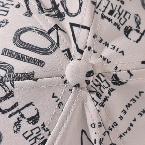 Macro detail of graffiti print baseball cap showing top button and premium stitching