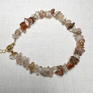 Macro detail of irregular natural quartz crystals with golden lobster clasp and chain