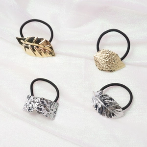 Minimalist metal leaf hair ties in gold and silver finish on soft white fabric