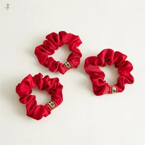 Detailed view of red satin scrunchies with golden Fu character charm for women