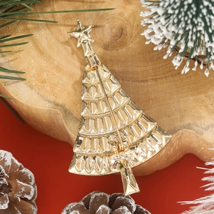 Golden Christmas tree brooch with metal pin back on a festive pinecone background