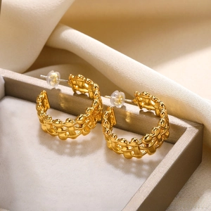 Detailed macro view of triple-layered gold C-shape hoop earrings with woven texture