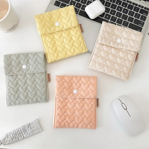 Flat lay of small quilted cotton heart pouches for pads and accessories in four colors