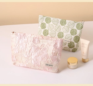 Close-up of pink jacquard and leaf print canvas cosmetic bags with metal ring zippers