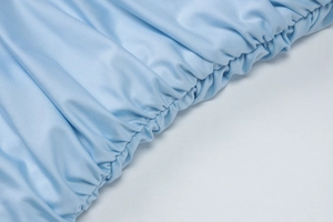 Dettaglio macro del tessuto azzurro con arricciature elastiche e trama in twill