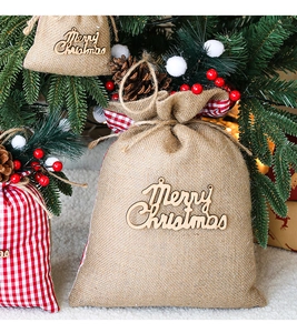 Close-up of burlap Christmas gift bags with Merry Christmas wooden signs and pine cones