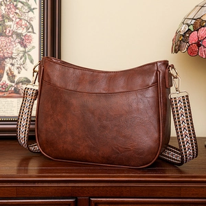 Dettaglio borsa a mezzaluna marrone vintage con tracolla geometrica e finiture dorate