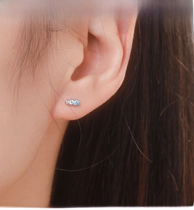 Close-up of S925 sterling silver stud earrings with blue and white zircon on ear