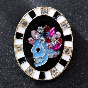 Vintage oval skeleton brooch with sky blue skull and multi-colored crystals on black pad