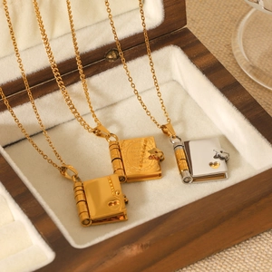 Detail of gold and silver openable book pendants with heart cutout on velvet display