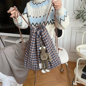 Detail of tweed checkered backpack with drawstring closure and green plush frog charm