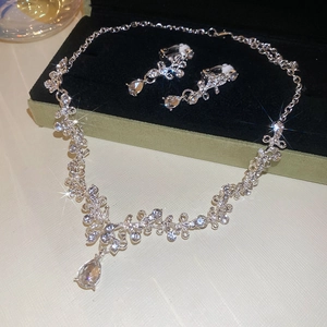 Detail of silver floral necklace and drop earrings set with crystals on black velvet