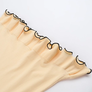 Primer plano detallado de textura de punto con volantes negros en el vestido crema