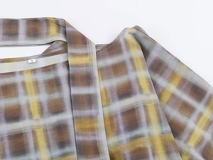 Détail de l'encolure et de la texture d'épaule de ce poncho tissé à carreaux tie-dye