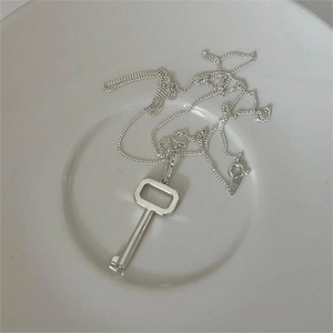 Minimalist S925 sterling silver key pendant necklace on a white ceramic plate