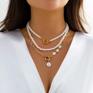 Detail view of multilayer pearl necklace with gold chain and T-bar toggle clasp on model