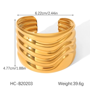 Detailed view of wide wave-textured gold stainless steel cuff with product dimensions