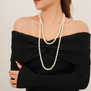 Close-up of elegant double-layer long pearl necklace worn with a black off-shoulder top
