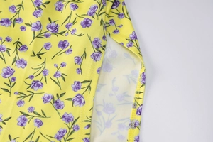 Detailed macro view of yellow floral print fabric and quality stitching of the summer dress