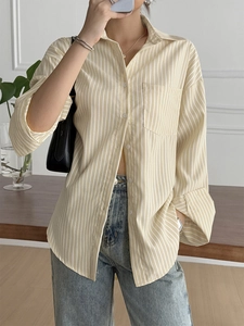 Detail of yellow and white striped long sleeve shirt featuring front pocket and loose fit