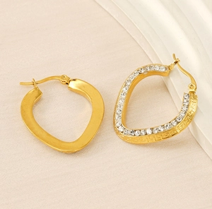 Detailed macro of gold plated hoop earrings featuring greek patterns and crystal stones