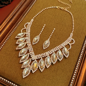Detailed close-up of champagne crystal teardrop tassel necklace and earring set on velvet