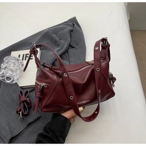 Close-up detail of burgundy Boston bag with silver zipper on a gray blazer