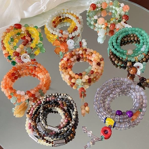 Detail von bunten Perlenarmbändern mit Lotusanhängern und Quasten auf einer Spiegelfläche