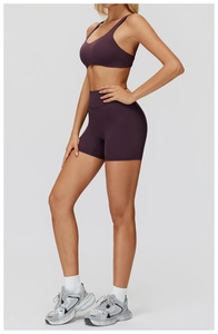 Detail of high-waist dark purple yoga set with cross-back sports bra and tight shorts