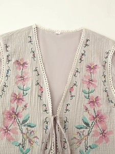 Close-up of floral embroidery and lace-up details on a bohemian autumn vest