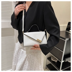 Detail showing the white crocodile pattern texture and metal clasp of the handbag
