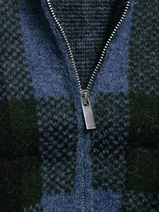 Macro shot of plaid knit jacket featuring fuzzy blue-black texture and metal zipper detail