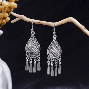 Macro detail of silver vintage bohemian earrings with tassels hanging on a wood branch