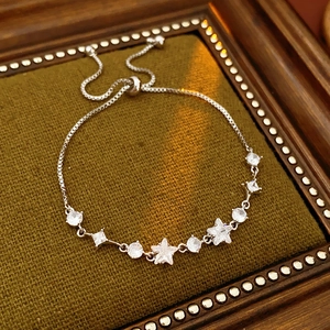 Detail of adjustable silver star and round zircon bracelet on green textured fabric