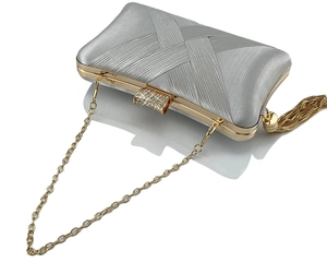 Detail of silver satin clutch featuring gold chain tassel and crystal-encrusted buckle