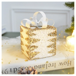 Close-up of a glowing Christmas gift box with gold glitter tree pattern and a white bow