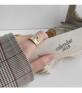 Nahaufnahme eines goldenen geometrischen U-Rings am Modell in minimalistischer Szene