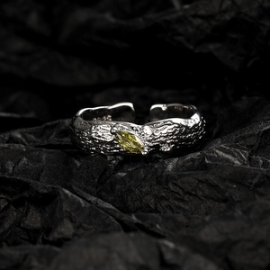 Lava texture silver open ring featuring an olive green marquise gemstone on black background