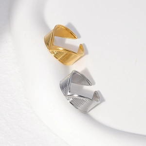 Detail shot of V-shaped open rings in gold and silver with textured stripe finish
