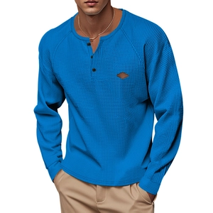 Detail of blue waffle knit Henry shirt with buttoned neckline and small leather patch