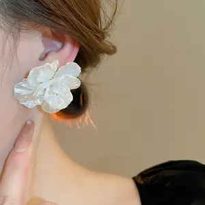 Elegant white shell flower earrings with pearl accent on model for sophisticated look