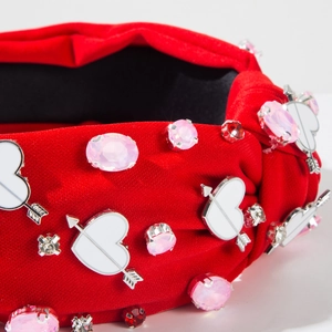Detail of red fabric headband with crystal heart, cupid arrow and turban knot