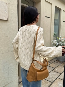Detail of the knit cable texture and loose fit design on a beige casual sweater