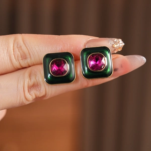 Detail of vintage square earrings with green enamel and a pink centered gemstone