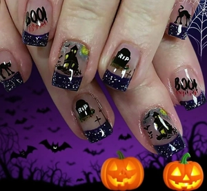 Close-up of Halloween press-on nails with black cat silhouettes and purple glitter tips