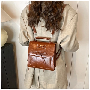 Detailed back view of a brown faux leather backpack with lace-up bow and thin straps