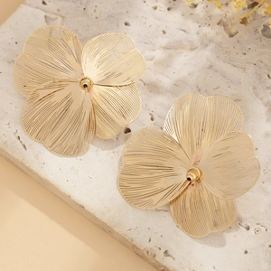 Macro detail of golden flower earrings with intricate hollow leaf veins on stone base