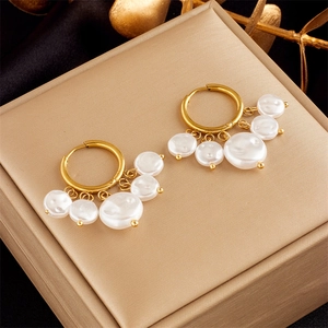 Close-up of gold drop earrings with white pearls on a luxury jewelry box display