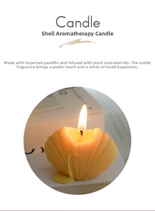 Close-up of a lit cream-colored shell-shaped scented candle with melting wax details