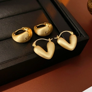 Close-up of geometric matte gold earrings showing brushed metal texture and V-shaped design
